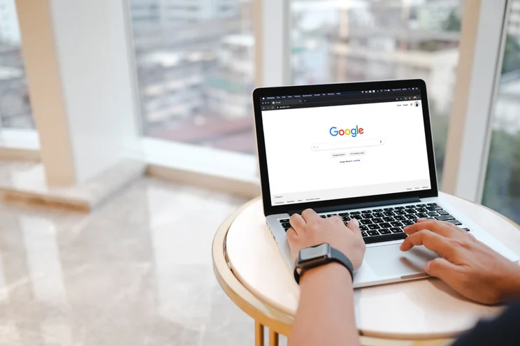 Person typing at a laptop showing the Google homepage