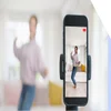 Photo of a woman behind a smartphone camera performing a TikTok dance trend