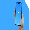 bluesky logo on phone being held in front of a blue background