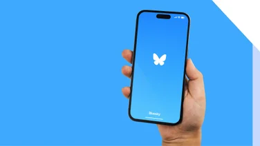 bluesky logo on phone being held in front of a blue background