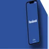 Phone with facebook logo on screen on a matching blue surface