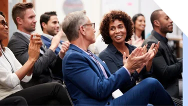 Businessmen and women sat down at a conference and clapping
