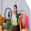 A woman in her clothes warehouse interacting with a camera in front of a ring light