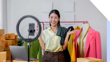 A woman in her clothes warehouse interacting with a camera in front of a ring light
