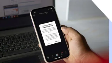 A hand holding a smartphone with a message from TikTok on the screen about the ban
