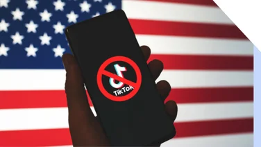 Hand holding phone with a banned TikTok logo, against a backdrop of the US flag