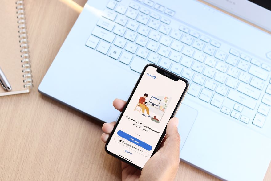 A hand holding a phone with the LinkedIn sign in screen on show