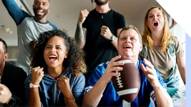A group of football fans watching the TV and celebrating
