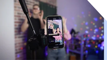 A man and a woman dance on a smartphone camera. A view of the phone screen standing on a tripod