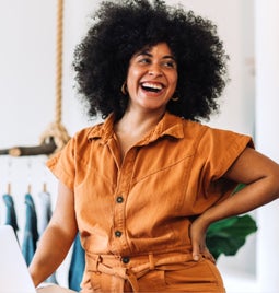 Women laughing as she stands next to her laptop