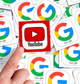 A finger pointing to a YouTube logo on top of many Google logos