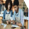 Two cafe workers looking concerned over paperwork and bills