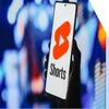 Photo of a hand holding a phone with the YouTube Shorts logo on screen