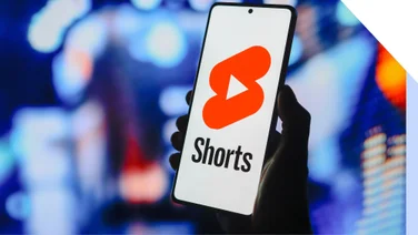 Photo of a hand holding a phone with the YouTube Shorts logo on screen