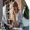 Woman holding her head in front of a desktop computer