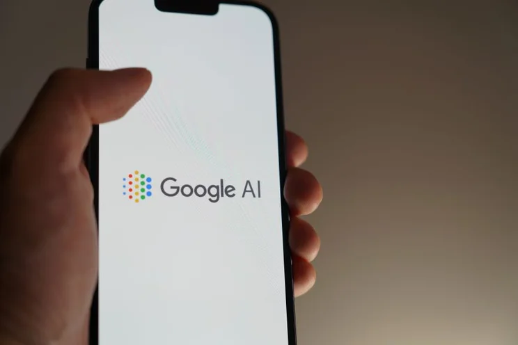 A hand holding a phone with the "Google AI" logo on screen