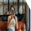 Woman sat on a sofa holding up a phone to take a photo
