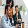 Three people working around a laptop together