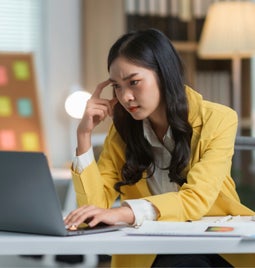 Woman looking puzzled and frustrated as she looks at a laptop