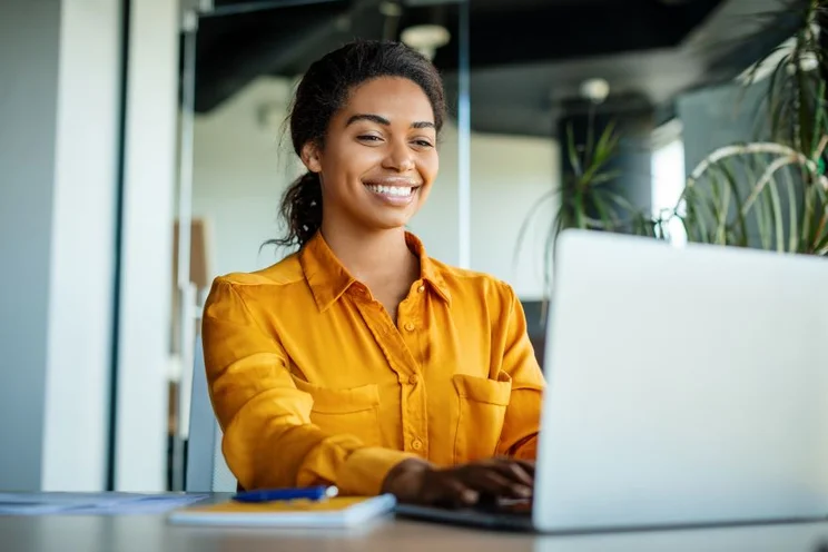 A woman smiling at her laptop