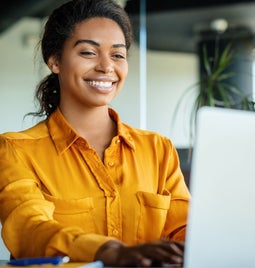 A woman smiling at her laptop