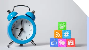 a blue alarm clock next to multicolored wooden blocks with social media icons on
