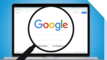 Magnifying glass hovering over a laptop screen showing the Google search homepage