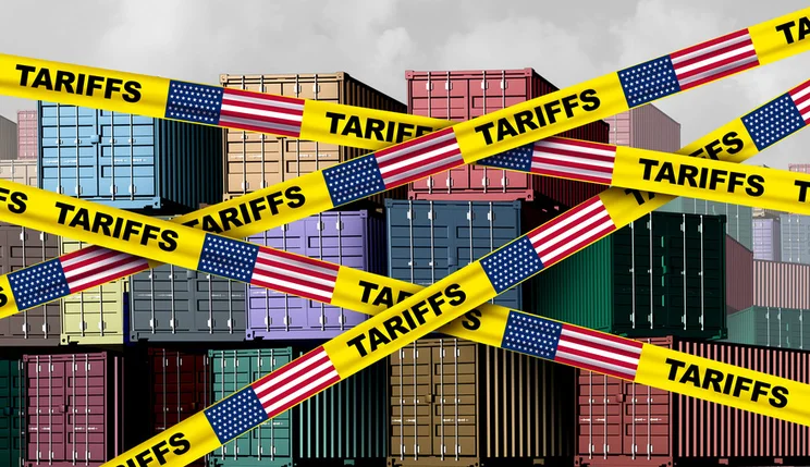 Cargo containers with yellow tape across the image showing the word "Tariffs" and the US flag