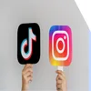 hands holding two lollypop sticks with tiktok and instagram logos on