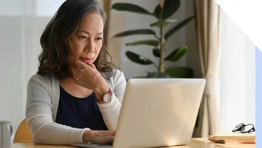 Woman looking thoughtful in front of laptop