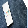 A phone with the google logo on the screen and text reading "E-E-A-T"
