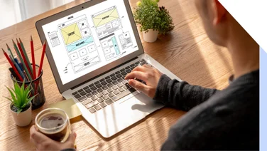 A man using his laptop with a homepage wireframe on the screen
