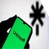 A hand holding a phone with the Linktree logo on screen