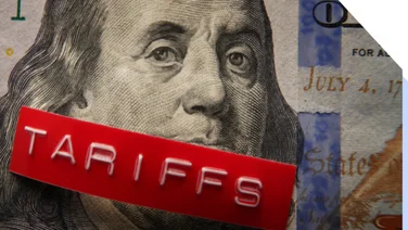 US money with a printed label on top saying tariffs