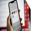 hand holding an iphone open on a homepage folder called social networking, containing X, Threads, Instagram, and Facebook apps