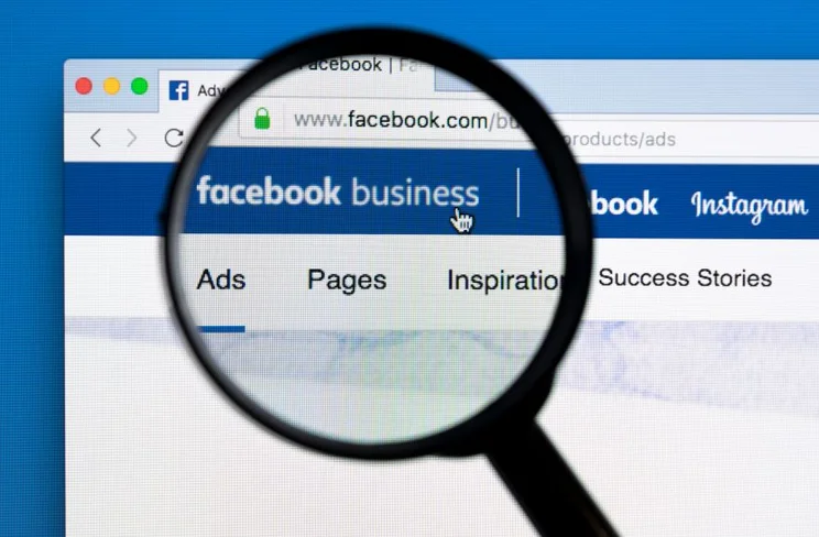 A magnifying glass positioned over a monitor with "Facebook Business" on screen