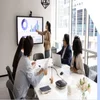 Colleagues sitting around a table watching a manager present on screen