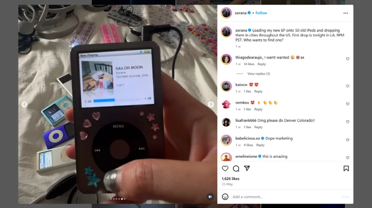 An Instagram photo post of a hand holding a decorated iPod displaying the song "Sailor Moon" on screen, surrounded by colorful accessories and other iPods.