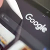 Closeup of a tablet screen with the Google logo and a stylus tapping it