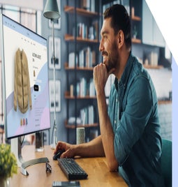 Man working at a computer showing a product page for a jacket