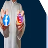 Person in white shirt holding up a sticker of the Facebook logo and the Instagram logo in each hand