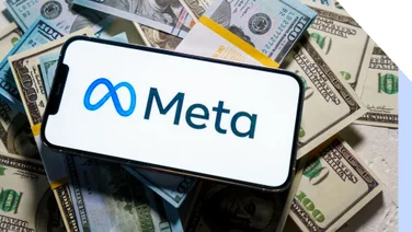 smartphone with meta logo on screen laying on top of a pile of cash