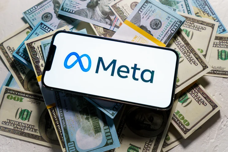 smartphone with meta logo on screen laying on top of a pile of cash