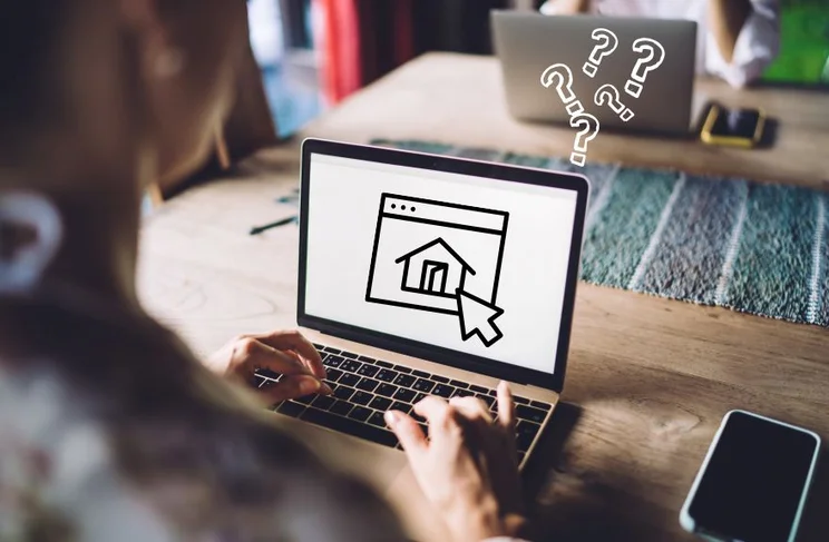 A person types on a laptop, displaying a home icon on the screen, surrounded by question marks, suggesting confusion or inquiry.
