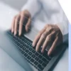 Hands typing at a laptop keyboard with a search bar image floating above
