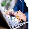 A person types on a laptop keyboard, surrounded by floating social media notifications and emojis representing interactions with friends.