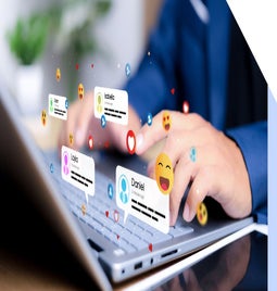 A person types on a laptop keyboard, surrounded by floating social media notifications and emojis representing interactions with friends.