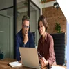 Man and woman working together at a laptop in an office space