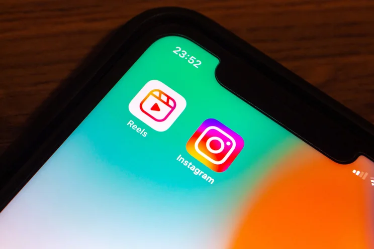Close-up of a smartphone screen displaying the Instagram and Reels app icons against a gradient background