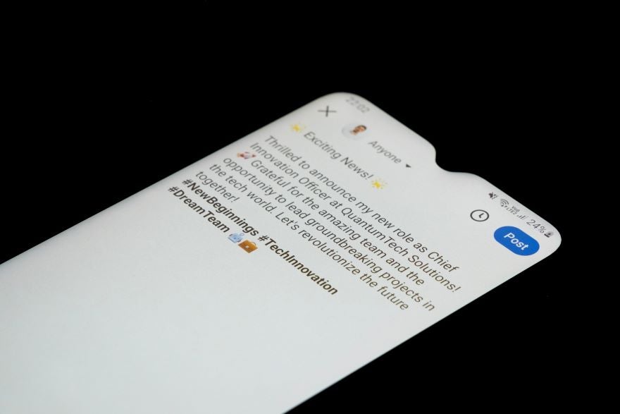 Close-up of a smartphone screen showing a celebratory social media post about a new role as Chief Innovation Officer at QuantumTech Solutions.